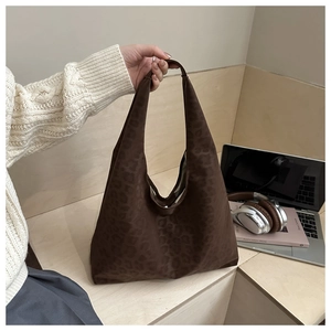Detailed shot of oversized leopard print tote bag being held in a cozy lifestyle setting