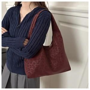 Detail shot of vintage leopard print tote bag in dark wine red on model shoulder