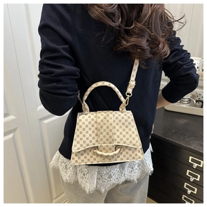 Close-up of cream geometric logo pattern crossbody bag with round ring flap and gold hardware