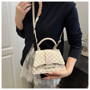 Detail of crossbody bag with beige M letter pattern and adjustable shoulder strap