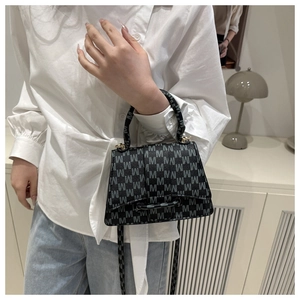 Detail view of the trapezoid handbag with letter M monogram pattern and carry handle