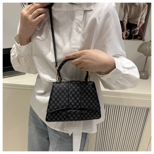 Detail of black crossbody bag with dot texture and gold hardware on white shirt model
