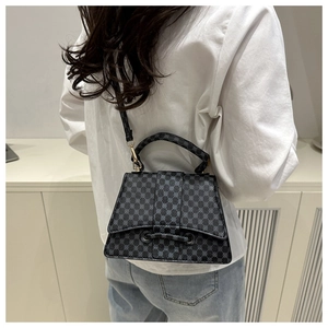 Rear view of model wearing a black trapezoid crossbody bag with gray geometric patterns
