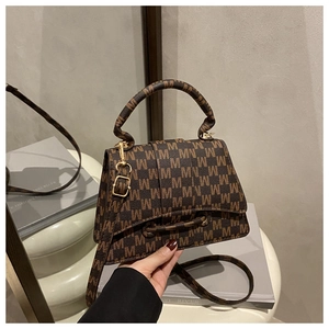Detail of vintage brown monogram handbag with adjustable strap and gold buckle