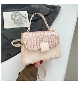 Detail of pink faux leather handbag featuring crocodile texture flap and square clasp