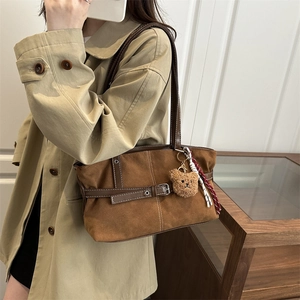 Brown suede tote bag with leather trim and bear pendant shown on beige trench coat