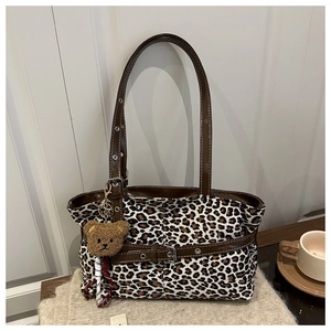 Detail of leopard print tote bag with brown leather strap and plush bear charm