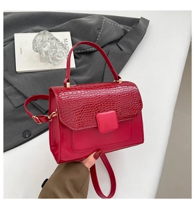 Detail of dark red crocodile embossed leather flap on a luxury crossbody handbag