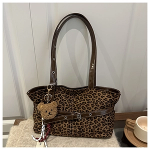 Macro detail of vintage leopard print tote bag with brown leather strap and teddy charm