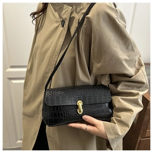 Détail du sac baguette noir motif crocodile avec un fermoir rotatif ovale doré