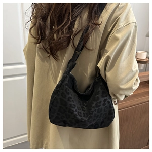 Close-up of black leopard print hobo bag with adjustable nylon shoulder strap for women