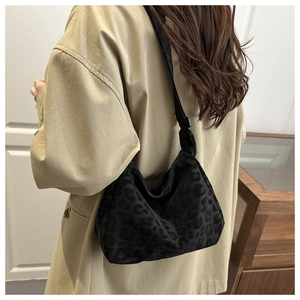 Detail of a vintage leopard print crescent bag with adjustable black fabric shoulder strap