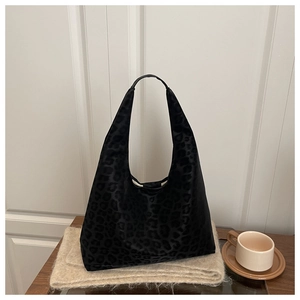 Close-up of black leopard print tote bag on a cozy wooden table with scarf and coffee
