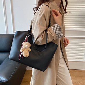 Minimalist black leather tote bag for women with a cute teddy bear charm and gold lettering
