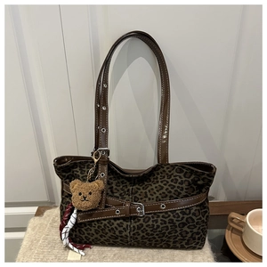Detail of leopard print canvas tote bag with adjustable brown leather straps and plush bear charm