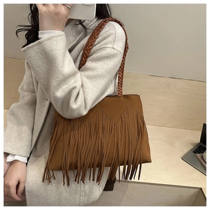 Dettaglio di una borsa tote in pelle scamosciata marrone con frange lunghe e manici intrecciati