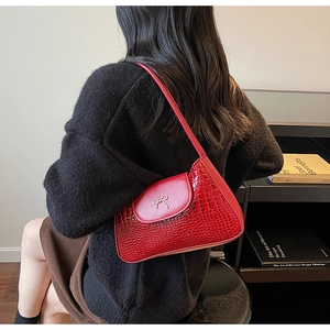 Detail of red crocodile pattern shoulder bag with a silver metallic bow decoration