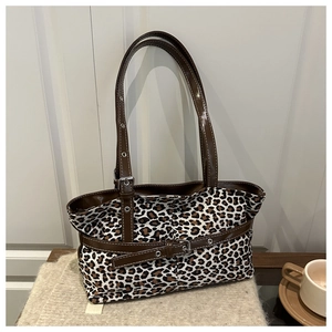 Close-up of leopard print tote bag featuring brown faux leather trim and metallic buckles