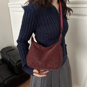 Deep burgundy crossbody bag with subtle leopard pattern and adjustable shoulder strap