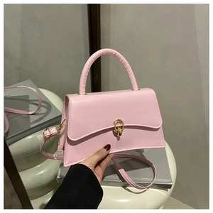 Detail of light pink crossbody bag with golden oval twist lock on white artistic stool