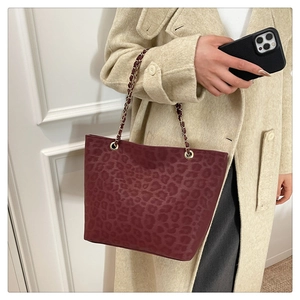 Detail of burgundy leopard print tote bag with gold chain and matte suede finish