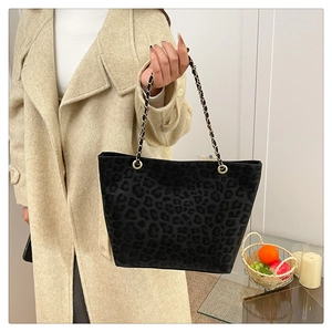Detail shot of black leopard print tote bag with gold chain strap on shoulder