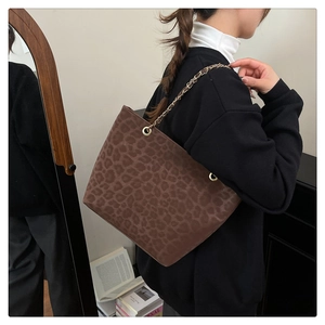 Detail of leopard print tote bag featuring a gold chain strap and suede texture finish