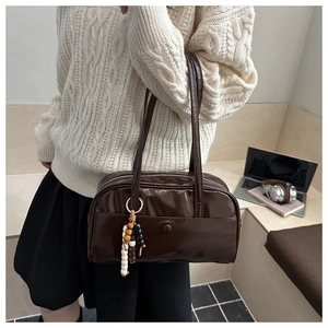 Brown faux leather shoulder bag with colorful beaded charm shown on a casual outfit