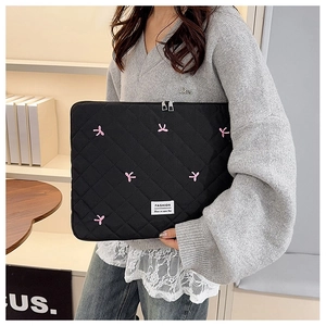 Détail d'une housse d'ordinateur matelassée noire avec broderie nœud rose et zip double