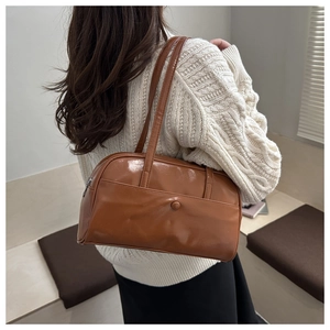 Close-up of caramel brown leather underarm bag featuring a magnetic front pocket detail