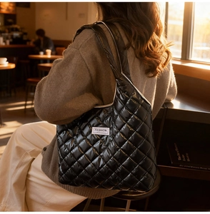 Gesteppte Tragetasche mit Rautenmuster und Label-Detail an der Schulter getragen