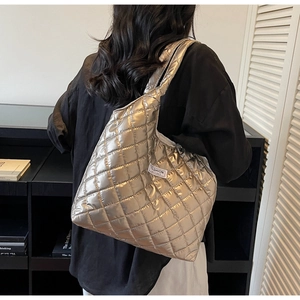 Detail of silver quilted tote bag with diamond pattern and fashion label on shoulder