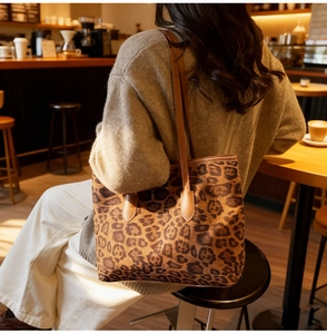 Detail of leopard print tote bag with brown leather straps in a cozy cafe setting
