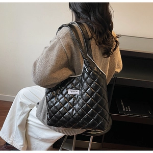 Detail of black quilted puffer tote bag featuring a Fashion Instinct brand label