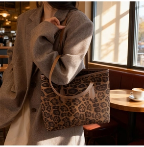 Detail of vintage leopard print tote bag with brown leather handles in warm cafe sunlight
