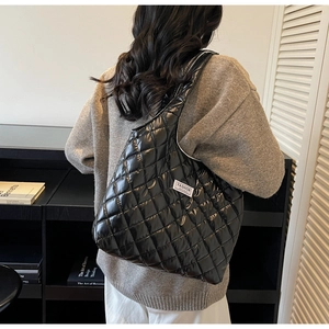 Detailansicht der großen schwarzen gesteppten Puffer-Tasche mit weißem Seitenetikett
