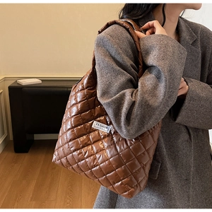 Side view of a brown quilted hobo bag featuring white Fashion Instinct lettering