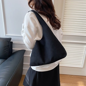 Minimalist black large capacity tote bag in faux suede shown on shoulder by female model