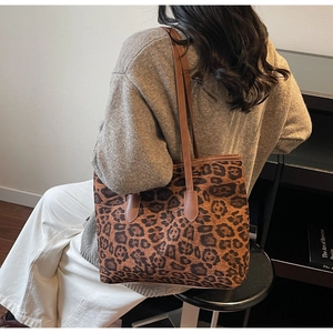 Detail of leopard print tote bag with brown faux leather straps worn by a model