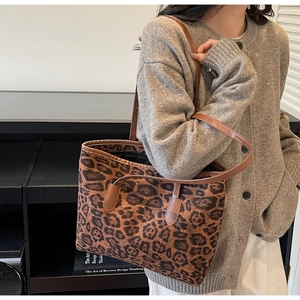 Close-up of leopard print tote bag with brown leather straps worn by a model