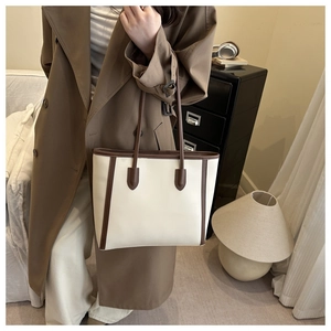 Fashionable beige tote bag with brown trim shown in a lifestyle commuter setting