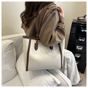 Close-up of contrast faux leather tote bag in cream and brown on a living room set