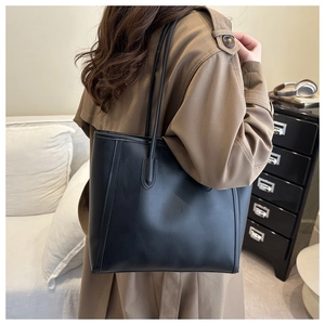 Close-up of a large black faux leather tote bag showing shoulder strap stitching details