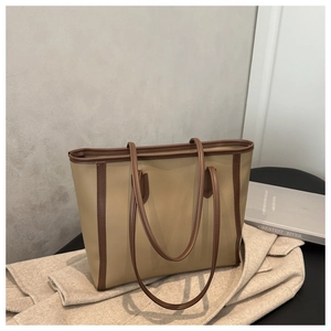 Detail view of a dual-tone commute tote bag with leather texture on a stylish chair