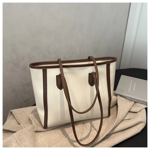Detail of a large cream tote bag with dark coffee contrast trim on a wool coat