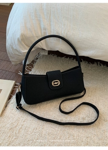 Detail of black underarm bag featuring matte leather texture and gold horsebit hardware