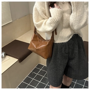 Brown leather tote bag styled on model wearing a beige sweater and wool shorts