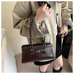 Détail d'un sac à bandoulière marron foncé en similicuir porté avec un trench beige