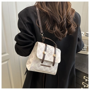 Détail du sac à bandoulière à carreaux avec motif d'ours et bandoulière en cuir brun