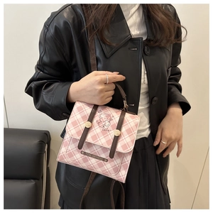 Detail of pink plaid shoulder bag with cartoon bear illustration and metal nameplate